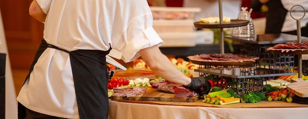 Kock ordnar kött, grönsaker och tillbehör på en buffé